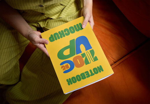 Woman sits on a comfortable couch, holding a blank front magazine ready for mockup