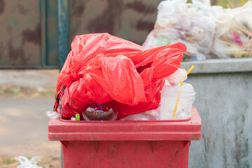 Garbage bins and containers full, overflowing, with bags falling on ground in residential area of Bordeaux, France, in a green container.