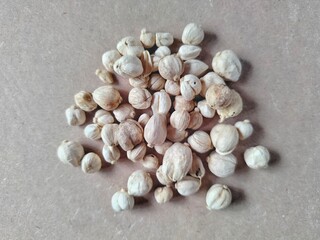 piles of white cardamom scattered over a light brown surface 