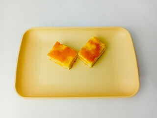 Cheesecake cut in half on square plate, isolated on white background.