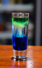 array shot glasses filled with vibrant and colorful drinks sits on a sleek bar counter. various hues reflect light and create an energetic atmosphere, perfect for a night out. 