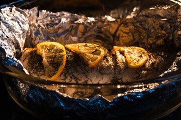 Baked in the oven in foil with spices, herbs and lemon in a baking dish, top view. Fresh baked walleye fish in foil for baking with vegetables, lemon and spices close-up. Pike-perch baked in foil. 