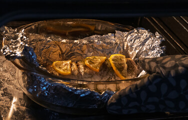 Baked in the oven in foil with spices, herbs and lemon in a baking dish, top view. Fresh baked walleye fish in foil for baking with vegetables, lemon and spices close-up. Pike-perch baked in foil. 