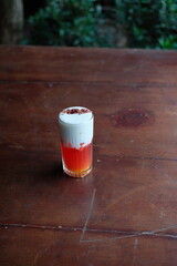 Refreshing layered drink with foam and garnish on rustic wooden table, perfect for summer menus and cocktail recipes, inviting and delicious