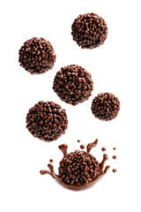 Chocolate balls, chocolatey, crunchy, and delicious.  Several round chocolate balls are suspended in the air, with a splash of chocolate below