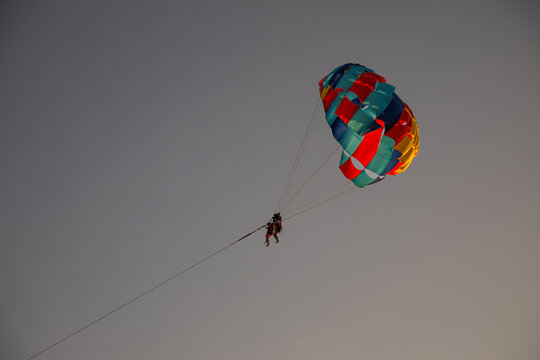 A tourist parachuting in the sky. Parasailing on the beach. Sunny evening.