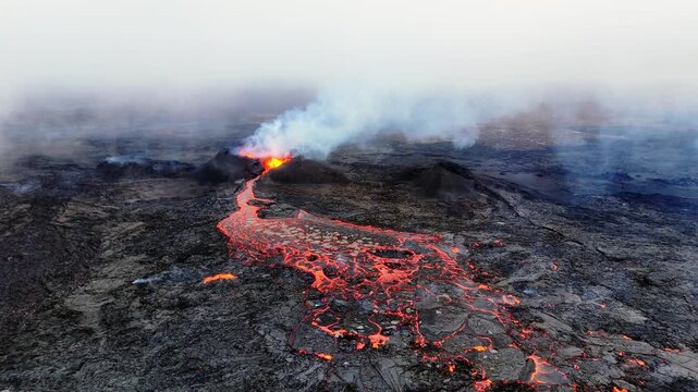 An aerial view of the active volcanic eruption at the Sundhn&uacute;kur crater row on Iceland's Reykjanes Peninsula, near Grindav&iacute;k. A river of glowing red and orange molten lava flows from a smoking crater.