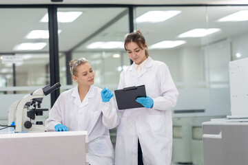 Fototapeta premium Two scientists collaborating in a modern laboratory while analyzing results on a digital tablet