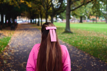 Rear portrait of woman in pink with bow on park alley
