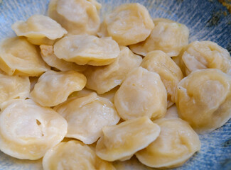 Homemade meat dumplings pelmeni with sour cream and herbs. Dumplings, filled with meat, ravioli, top view with space for your text. High quality photo