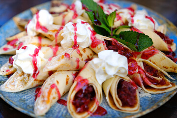 Crepes with ricotta cheese and fresh strawberries on pink pastel background, top view, copy space. Delicious crepes, thin pancakes. High quality photo