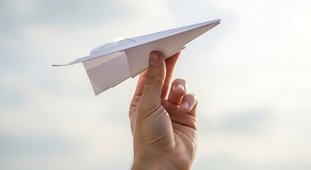 Hand Holding Paper Airplane Against Bright Sky with Sunlight
