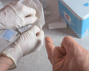 Close-up of a medical professional  treating a minor injury, cut on a patient's finger, symbolizing...