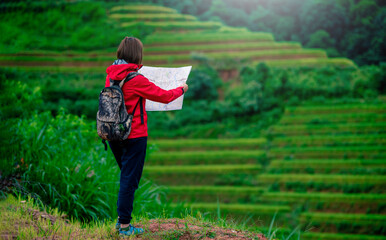 Young women backpacker looking to the map on rice fields terraced in Mu Cang Chai, YenBai, Vietnam.