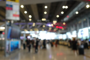 Blurred view of passengers and people at  International Airport. Travelers walking and checking flight information boards in the terminal. Busy atmosphere of people with luggage, lights, and airport.