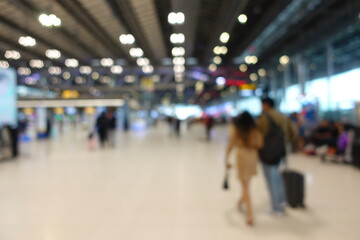 Blurred view of passengers and people at  International Airport. Travelers walking and checking flight information boards in the terminal. Busy atmosphere of people with luggage, lights, and airport.