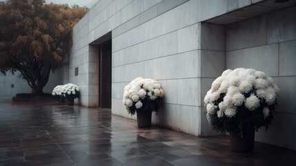 Elegant white chrysanthemums adorn the modern stone entrance of a building with autumn foliage in the background