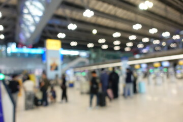 Blurred view of passengers and people at  International Airport. Travelers walking and checking flight information boards in the terminal. Busy atmosphere of people with luggage, lights, and airport.