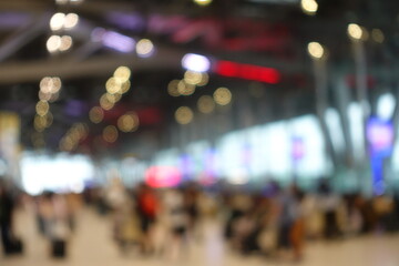 Blurred view of passengers and people at  International Airport. Travelers walking and checking flight information boards in the terminal. Busy atmosphere of people with luggage, lights, and airport.