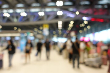 Blurred view of passengers and people at  International Airport. Travelers walking and checking flight information boards in the terminal. Busy atmosphere of people with luggage, lights, and airport.