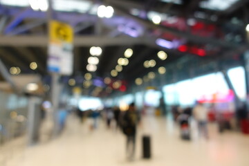 Blurred view of passengers and people at  International Airport. Travelers walking and checking flight information boards in the terminal. Busy atmosphere of people with luggage, lights, and airport.