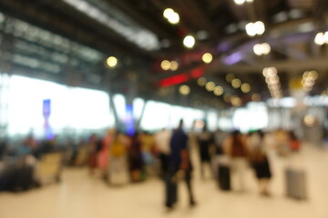 Blurred view of passengers and people at  International Airport. Travelers walking and checking flight information boards in the terminal. Busy atmosphere of people with luggage, lights, and airport.