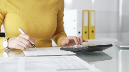 Woman doing financial paperwork, calculating budget, scrutinizing documents, and reviewing expenses with magnifying glass. Audit and taxes in business
