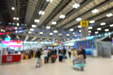 Blurred view of passengers and people at  International Airport. Travelers walking and checking flight information boards in the terminal. Busy atmosphere of people with luggage, lights, and airport.