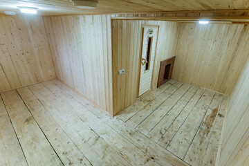 versatile woodpaneled corner room with visible doorway and raw plank floor, soft ceiling light...