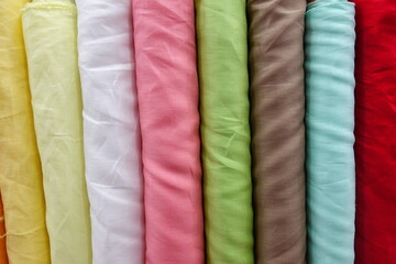 "Colorful Fabric Rolls Displayed in a Textile Market"
A vibrant and diverse selection of fabric rolls in various textures, colors, and patterns displayed vertically in a fabric store. 