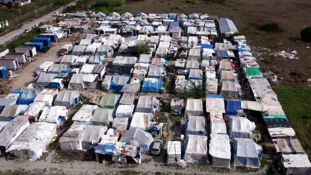 An aerial view of a makeshift migrant camp.
Shacks constructed from various materials. Humanitarian and social issues related to migration, poverty, and population displacement.