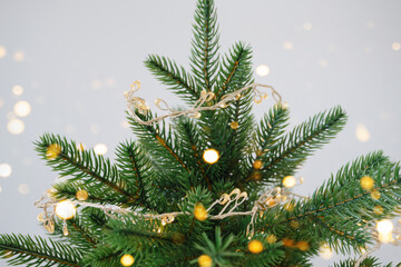 Decorated christmas tree with lights and bokeh against gray background Close-up