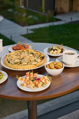 A Beautiful Array of Assorted Delicious Dishes Arranged on a Wooden Table Alongside Coffee