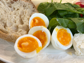 Slices of bread and halved eggs arranged on white plate with fresh greens. Simple breakfast scene showing warmth and nourishment.