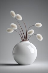 Fluffy white plant stalks arranged in a round ceramic vase.