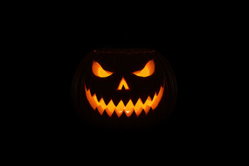 Fototapeta premium Dramatic Scary Jack o' lantern Face with Glowing Orange Light in Dark Background, Halloween Horror Night Photography