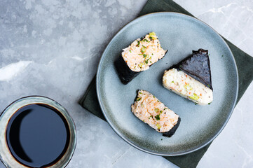 Traditional Japanese snack onigiri, rice balls wrapped in nori seaweed, served on marble.