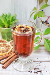 Hot tea on the table, cinnamon stick and orange slices around.