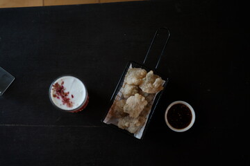Delicious fried snacks with dipping sauce and creamy drink on dark table, perfect for restaurant menus or food blogs promoting tasty treats