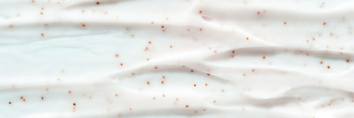 Close-up of textured white cream with brown speckles on smooth surface.