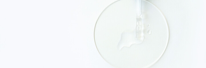 Transparent liquid in dropper on glass petri dish for laboratory experiments.