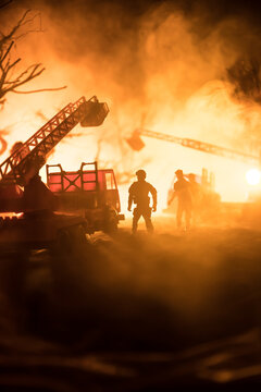 A tabletop diorama of a tragic California wildfire, set in Pacific Palisades near Malibu. Dramatic flames and smoke rise as firefighters battle the blaze