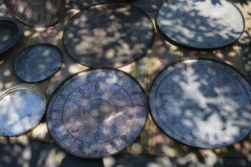 Antique copper trays and dishes with detailed engraving displayed at a flea market in Tbilisi. Warm sunlight and soft shadows create a cozy, authentic atmosphere.