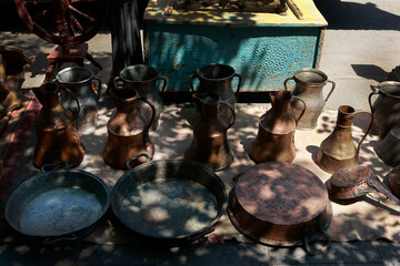Antique metal household items, jugs and trays displayed at the famous Dry Bridge flea market in Tbilisi, Georgia. Rare antique collectibles reflecting local culture and craftsmanship.