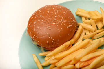 Hamburger with meat and vegetables and French fries. Fast food. Hamburger on a plate.