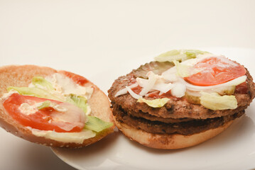 A nibbled hamburger with meat and vegetables. Fast food. Hamburger on a plate. Fast food scraps.