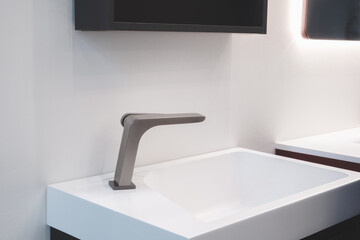 Interior of a bright bathroom with a white ceramic sink, modern faucet, and mirror