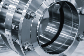 Stainless steel shiny rings connected with long bolts as part of industrial piping system, industrial concept background