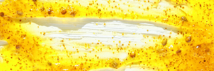 Close-up of yellow honey and pollen texture with seed details in bright light.