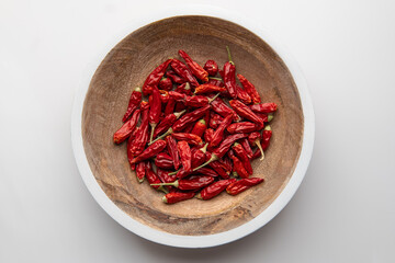 Dried Red Chili Peppers in Wooden Plate with White Rim on White Background